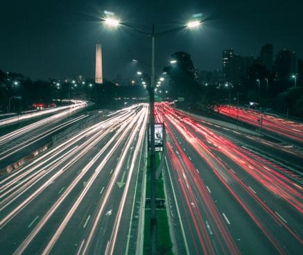 Esta imagen contiene una carretera iluminada, con dos carriles en cada dirección.