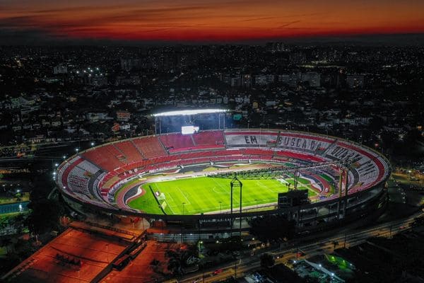 Esta imagen muestra un estadio de fútbol con luces nocturnas encendidas durante la noche.